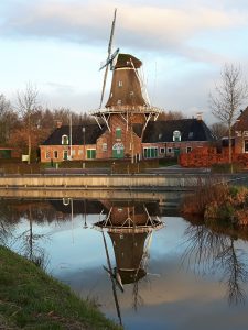 Olie- en Korenmolen Woldzigt met haar nieuwe kleuren zich spiegelend in de Schipsloot